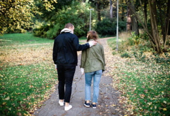 man och kvinna promenad ryggar hand på axel