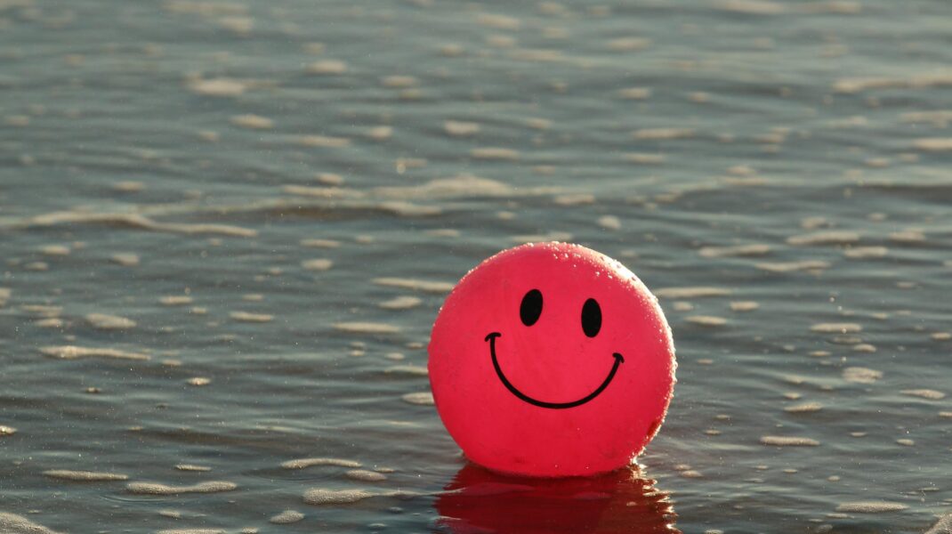 röd boll med glad mun och ögon flyter i vatten
