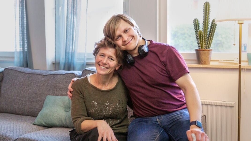 Medarbetare sitter i en soffa och omfamnas av en omsorgstagare