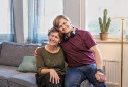 Medarbetare sitter i en soffa och omfamnas av en omsorgstagare