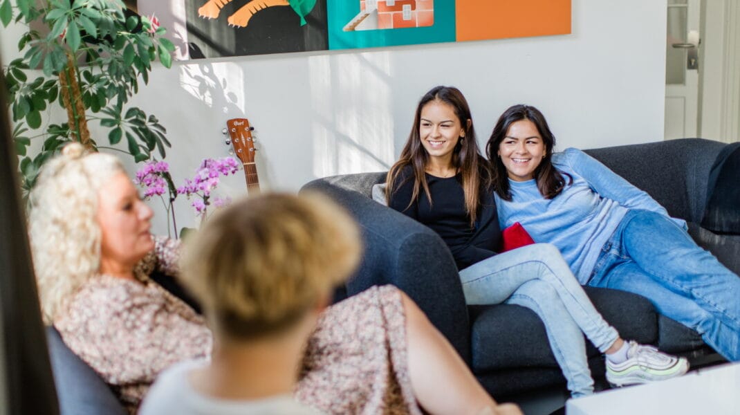 Två tjejer sitter i en soffa med vuxna