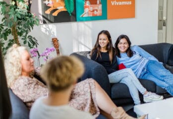 Två tjejer sitter i en soffa med vuxna