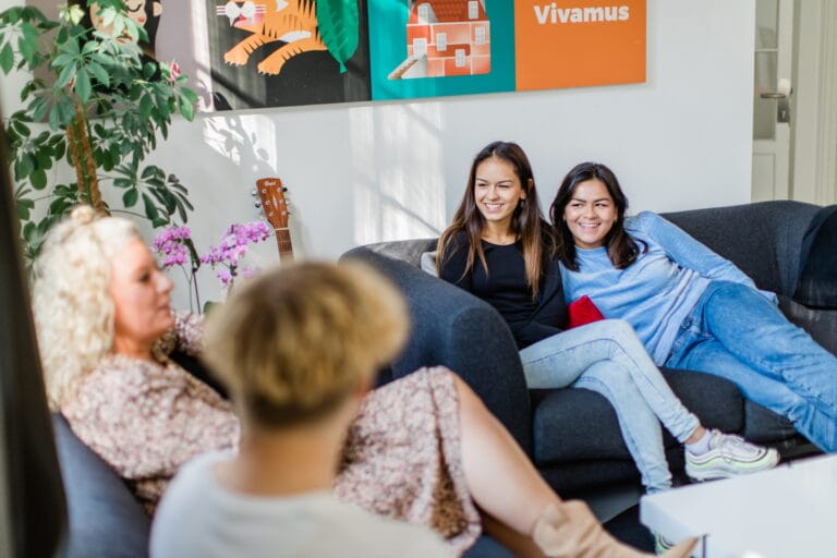 Två tjejer sitter i en soffa med vuxna