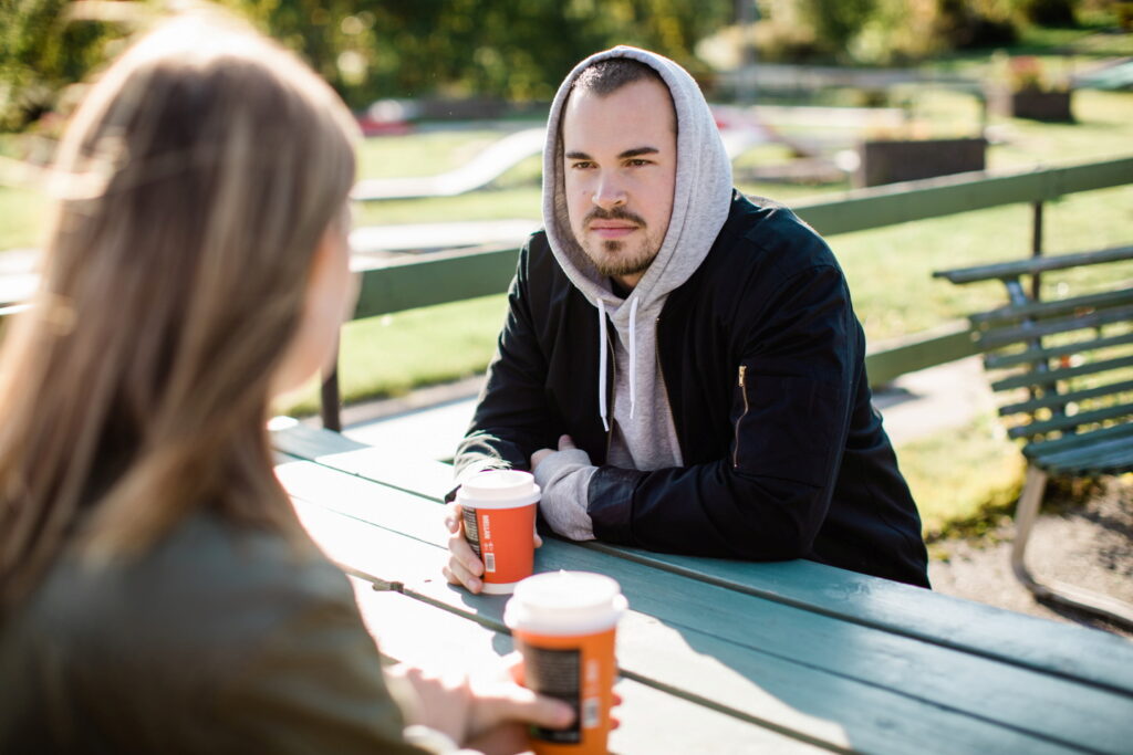 man och kvinna dricker kaffe vid en bänk utomhus