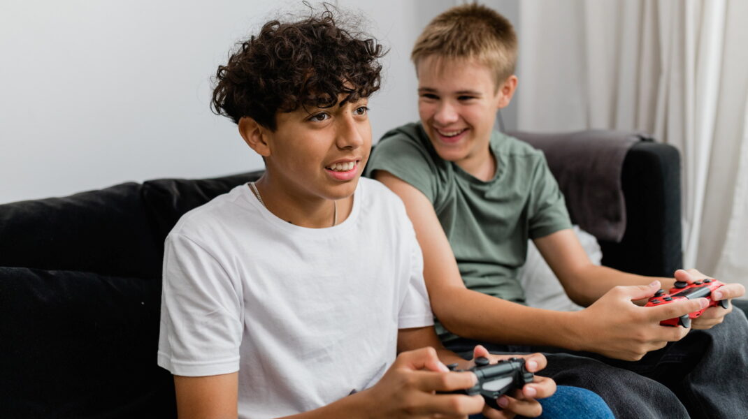 Två killar spelar dataspel i en soffa