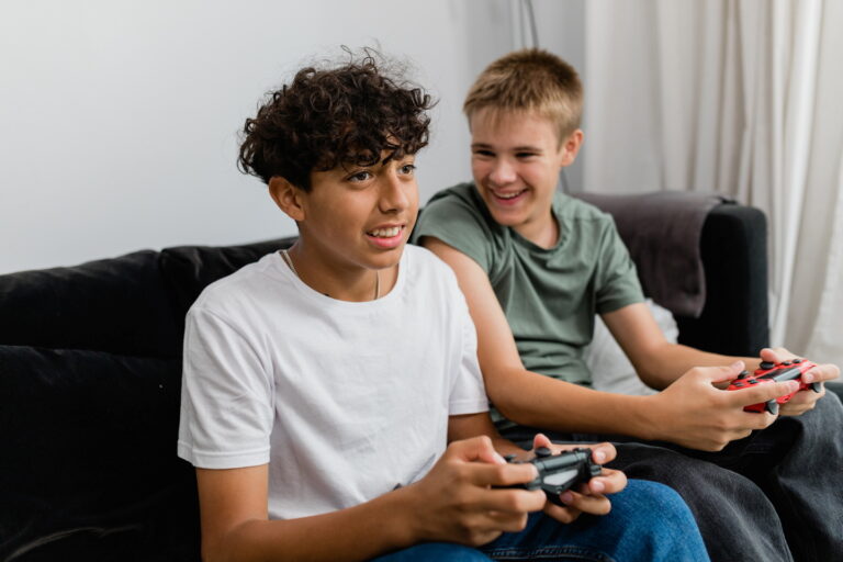 Två killar spelar dataspel i en soffa